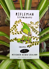 Enamel pin packaging with a Tītipounamu bird illustration on a white background, surrounded by green leaves.